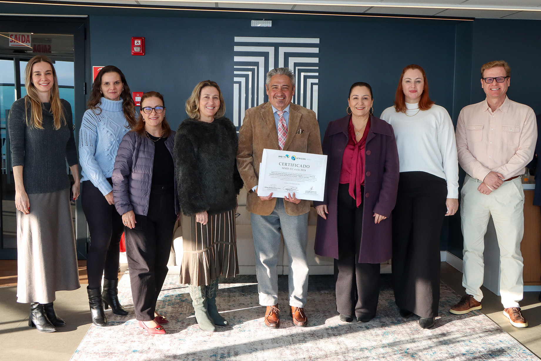 Foto horizontal com os integrantes das comissões no âmbito do TCE/SC, que estão em pé. O conselheiro Aderson Flores está segurando o certificado.